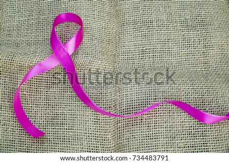 Health care and Medicine Concept - A pink ribbon isolated on a brown background. Breast cancer awareness pink sign symbol for help illness people