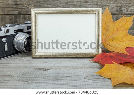 retro camera and photo frame on wooden background with colorful fallen leaves. memories concept. 