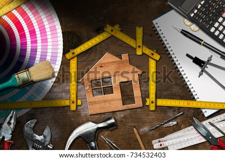 Home improvement concept - Wooden model house with folding ruler, work tools and a calculator on a wooden desk Royalty-Free Stock Photo #734532403