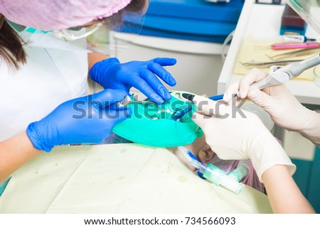 Close-up of two dentists in uniform of imedicine sterile gloves doing surgery for dental treatment to a child, a dentist cares for teeth from caries