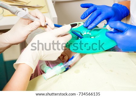 Close-up of two dentists in uniform of medicine sterile gloves doing surgery for dental treatment to a child, a dentist cares for teeth from caries