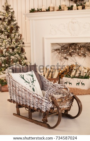 Interior of a living room with a fireplace, decorated with Christmas tree and wicker sleds