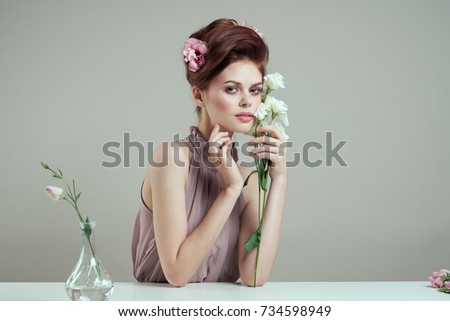 cute woman with hair and makeup in her hand flowers on a light background, beauty                               