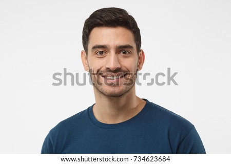 Close up portrait of smiling handsome guy in blue t-shirt isolated on gray background Royalty-Free Stock Photo #734623684