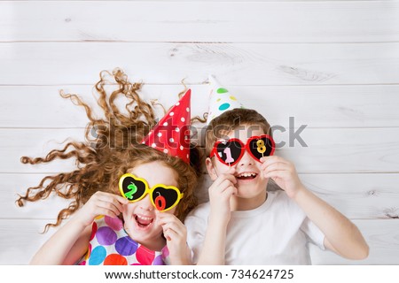 Cute children with sunglasses, hold candles 2018, lying on the wooden floor. High top view. Royalty-Free Stock Photo #734624725