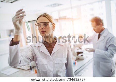 Two scientists are working in laboratory. Young female researcher and her senior supervisor are doing investigations with test tubes. Royalty-Free Stock Photo #734632957