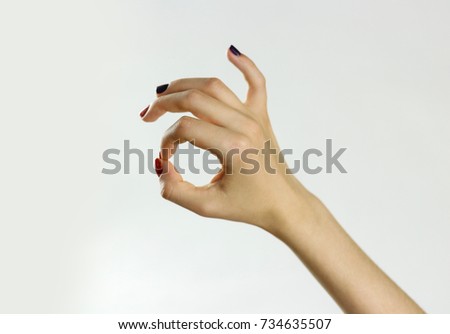 Female hand shows sign OK. Isolated on gray background. Closeup.