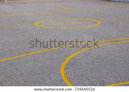 cement basketball court with yellow paint lines