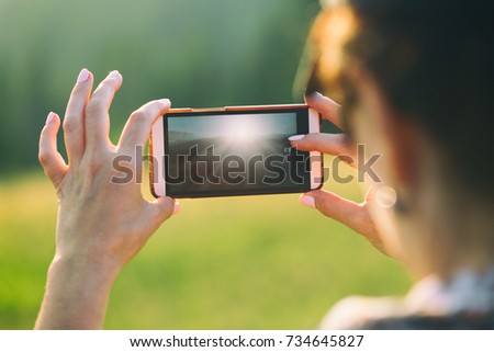 A woman is making a photo on a smartphone.