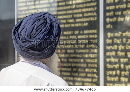 Indian Sikh with turban, reading sacred scriptures, New Delhi, India, in english and hindi in Gurudwara Bangla Sahib complex