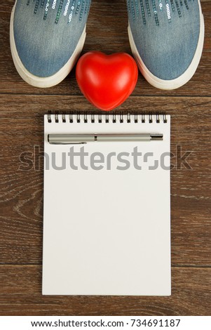 Women's shoes, heart, pen and white notebook top view