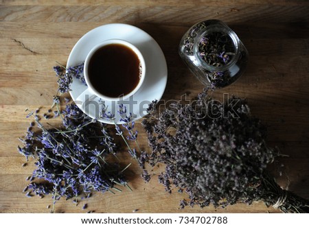 Black tea or coffee in a white cup on board with dried herbs