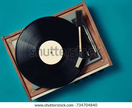 Retro vinyl player on a blue background. Entertainment 70s. Listen to music. Top view. Royalty-Free Stock Photo #734704840