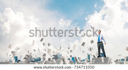 Businessman keeping hand with book up while standing among flying paper documents with cloudly sky on background. Mixed media.