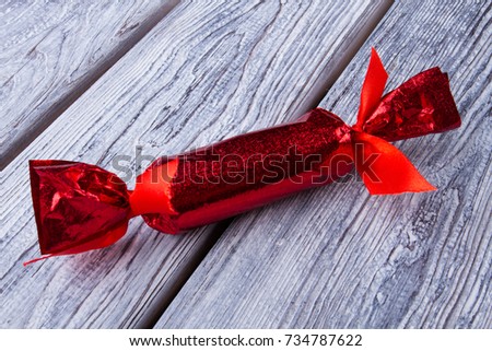Candy shaped gift box made of red sparkling paper on gray wooden table. DIY, creative ideas for Christmas party.