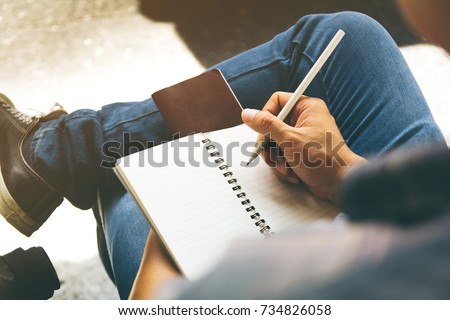 Close-up of a male hand writing on an blank notebook with a pencil. Royalty-Free Stock Photo #734826058