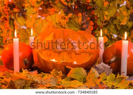 Halloween pumpkin lantern with dry leaves and candles