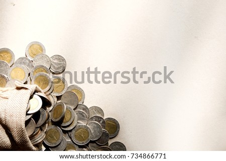 Coins are placed on sackcloth. While there was a bag of scattered coins in the bag, Concept of saving money for future.