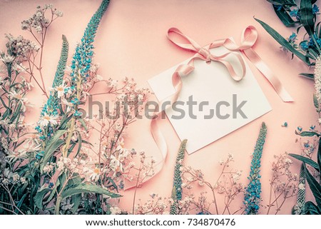 Blank white paper card with flowers on pastel background, top view. Festive greeting card