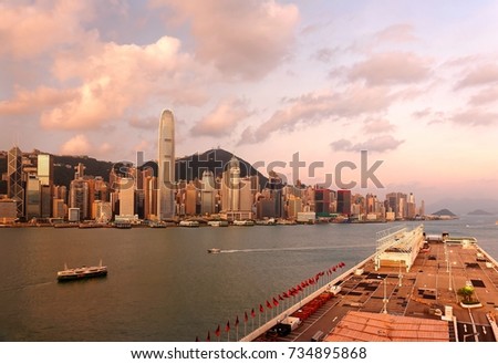 Morning scenery of Hong Kong at sunrise with International Finance Center (IFC) among skyscrapers by Victoria Harbour & Harbour City in foreground extruding into the seaport under dramatic dawning sky