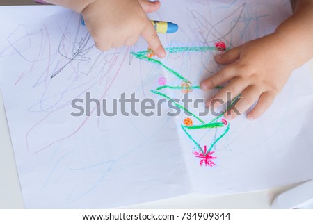 Baby hand of Little girl  drawing Christmas tree. A child draws a Christmas drawing. Copy space.