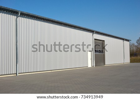 Modern gray warehouse with sheet metal cladding and large roller door Royalty-Free Stock Photo #734913949