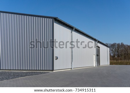 Modern gray warehouse with sheet metal cladding and large roller door Royalty-Free Stock Photo #734915311