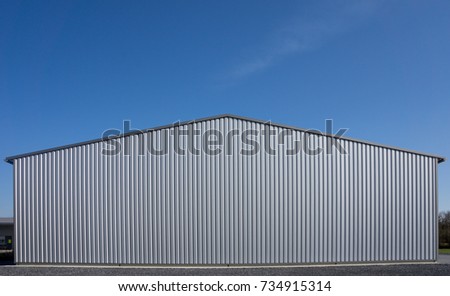 Modern gray warehouse with sheet metal cladding and large roller door Royalty-Free Stock Photo #734915314