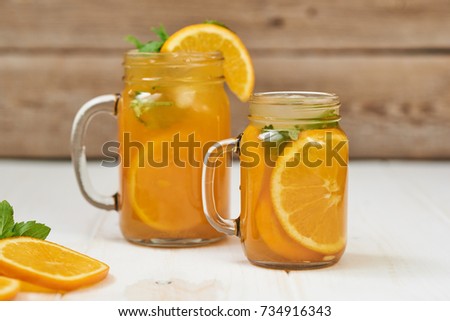 Non-alcoholic orange cocktail in a glass jar on a wooden background. Healthy eating concept. Selective focus with copy space.