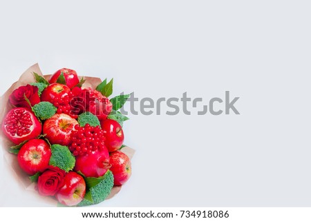 Fresh red fruits in bouquet on white background. Pomegranates (Punica granatum), apples, broccoli, viburnum. A useful gift for a healthy food detox diet. The natural background.