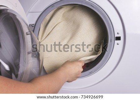 A girl washes clothes in the washing machine
