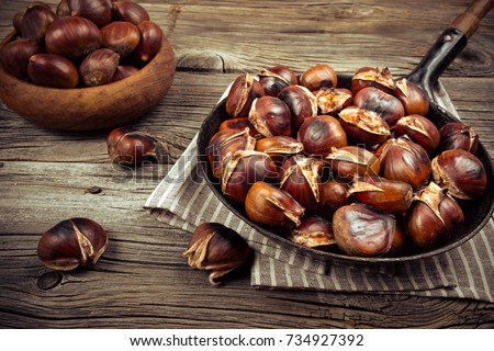 chestnuts in a pan on a wooden background Royalty-Free Stock Photo #734927392