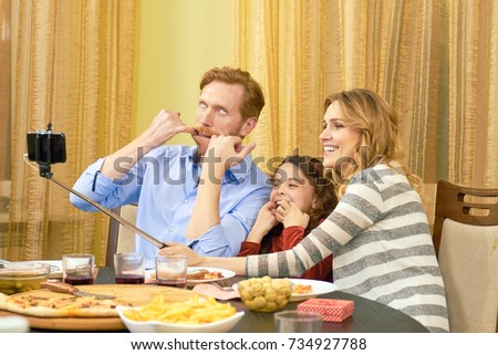 Family taking a funny selfie. Parents with daughter having dinner.