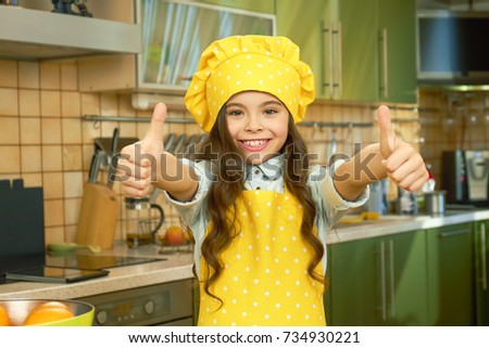 Happy girl in chef uniform. Smiling child showing thumb up. What makes a great cook.