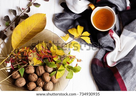 autumn picture with yellow, red and orange leaves, a cup of tea, a scarf. Cup of tea and autumn leaves on a white wooden table 