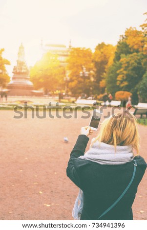 young girl takes a picture of a monument on a smartphone. Toned
