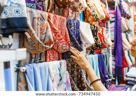 Young Woman Shopping For A New Scarf and choosing colorful fabric in bazar Royalty-Free Stock Photo #734947450