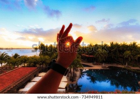 sunset between fingers formation of sun rays in a resort in Mauritius island. Beautiful sky and landscape with a pool and the ocean.