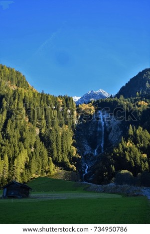 Beautiful waterfall in the Austria in the autumn with snowy mountains in the background