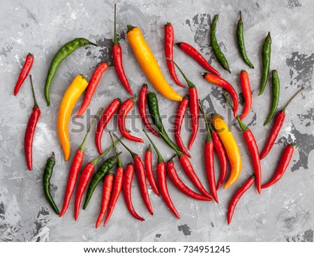 Assorted set of different colors hot chili peppers on grey marble stone surface. Mexican mix of green, yellow and red peppers, Cooking concept. Spicy kitchen ingredients.  Top view.