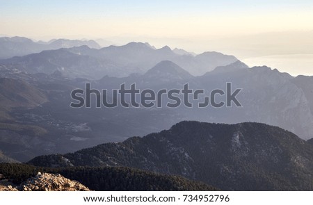 View from the top to the mountain peaks during the sunrise with deep shadows and bright areas