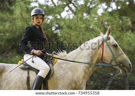 Young brunette beauty jokey girl riding horse in the park