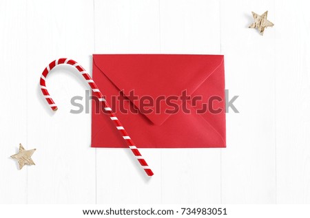 Christmas mockup scene with red envelope, candy cane decoration and stars made of birch bark on white wooden background. Empty space for your text, top view.