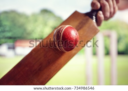 Cricket batsman hitting a ball shot from below with stumps on cricket pitch