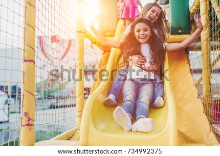 Little pretty girls having fun outdoor. Playing in children zone in amusement park. Royalty-Free Stock Photo #734992375