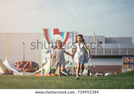 Little pretty girls having fun outdoor. Two cute girls are running on green grass. Best friends.