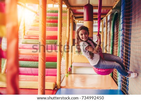 Little pretty girl is having fun outdoor. Playing in children zone in amusement park. Royalty-Free Stock Photo #734992450