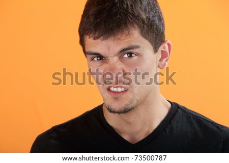 Latino teen on orange background clenches his teeth