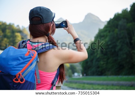 Image from back of brunette tourist photographing mountain