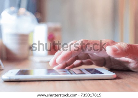 Hand using smart phone in coffee shop

